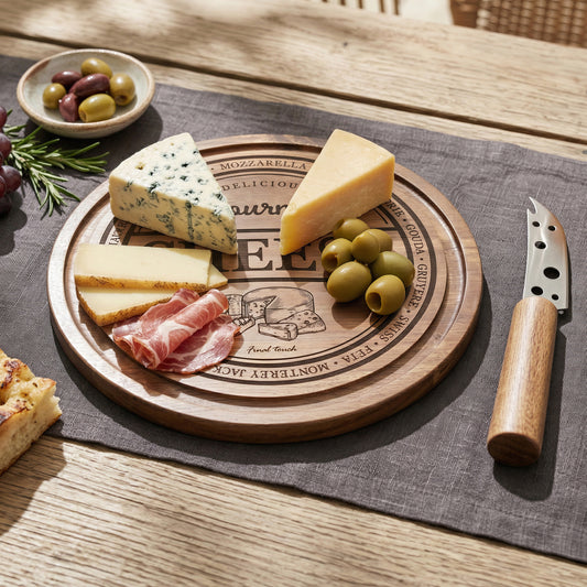 Wooden cheese board set with assorted cheeses, meats, and fruits on a wooden table.