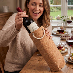Final Touch eco-friendly cork wine bottle bag with rope handle being opened at a dinner table setting.