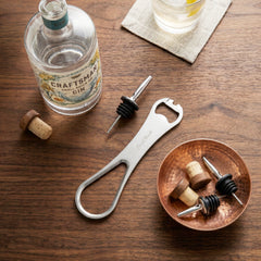 Final Touch ProBlade+ Speed Bottle Opener and liquor spout remover tool on a wooden bar top.