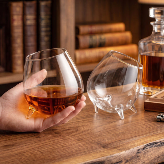 Final Touch set of 2 tilted cognac glasses displayed on a wooden table with liquor decanter and cigars