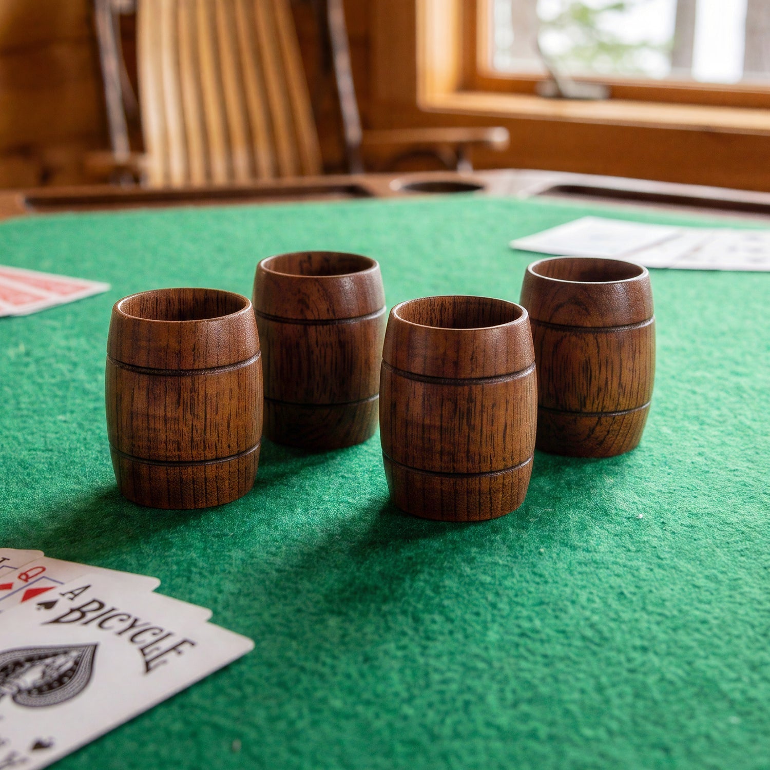 Set of 4 Final Touch wooden whiskey barrel shot glasses on a green felt poker card table in a rustic Muskoka lakefront cottage.