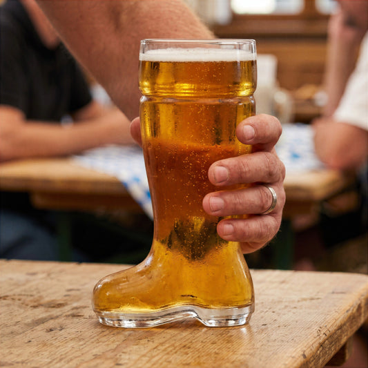 Final Touch Das Beer Boot Glass filled with golden lager, held by a hand on a wooden pub table.
