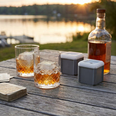 Final Touch Yarai Double Old-Fashioned Glass Set with foggy square ice cubes on a rustic outdoor table at sunset