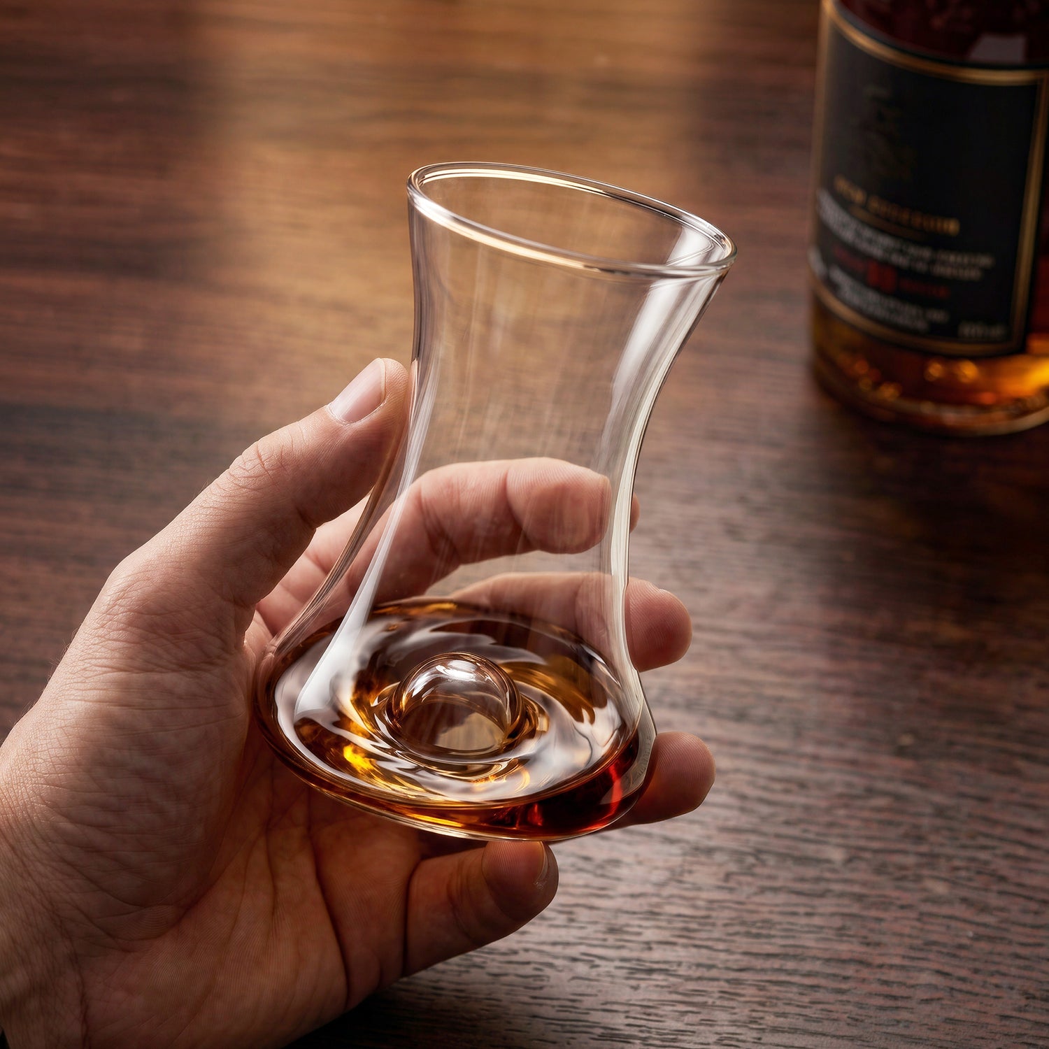Close-up of a hand gently holding and swirling rum in a Final Touch tasting glass