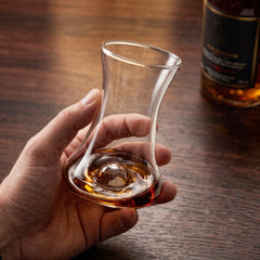 Close-up of a hand gently holding and swirling rum in a Final Touch tasting glass