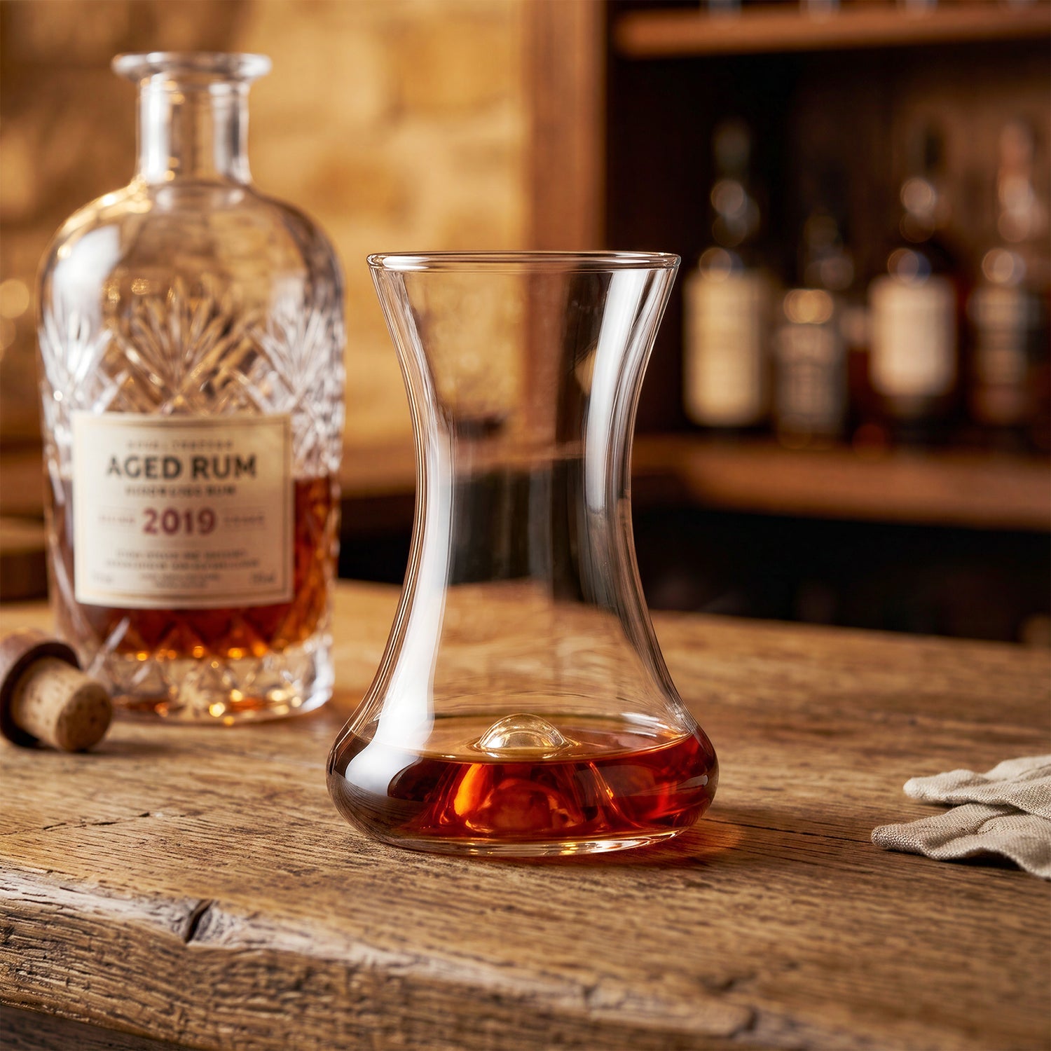 Tasting of aged rum from the Final Touch Rum Taster Glass and a vintage style 2019 rum bottle in a warm bar setting.
