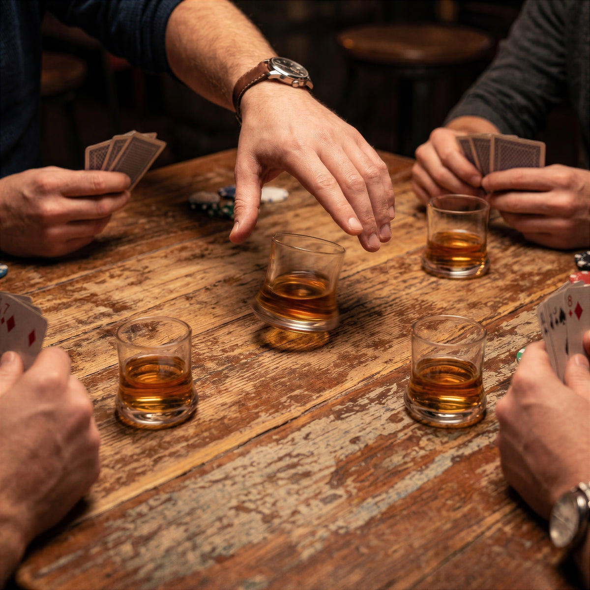 Action shot of a hand spinning a small glass from the Final Touch Revolve Revolving Shot Glass Set of 4 during a card game with friends.