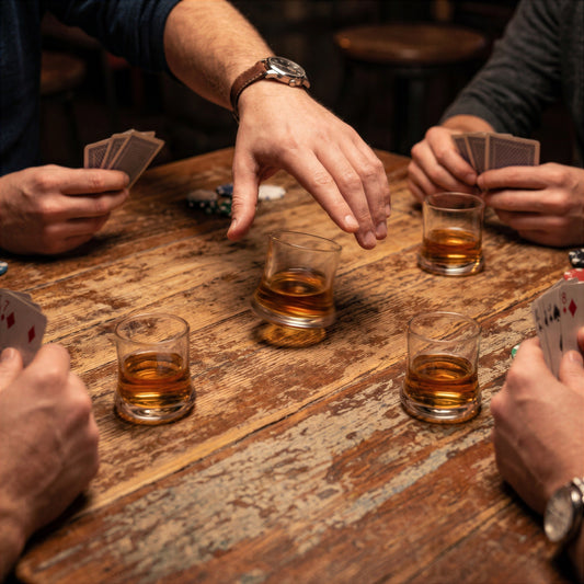 Action shot of a hand spinning a small glass from the Final Touch Revolve Revolving Shot Glass Set of 4 during a card game with friends.