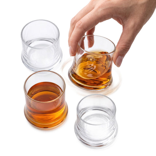 Final Touch Revolve revolving shot glass set of 4, showing a hand spinning a whiskey-filled rolling base glass for dynamic barware presentation.