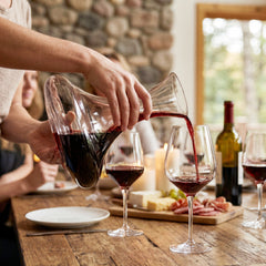 Final Touch Revolve Revolving Wine Decanter filled with red wine, being poured into a crystal glass during a rustic dinner party setting