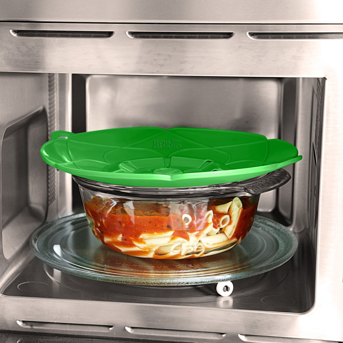Green lid rests on glass bowl inside microwave.