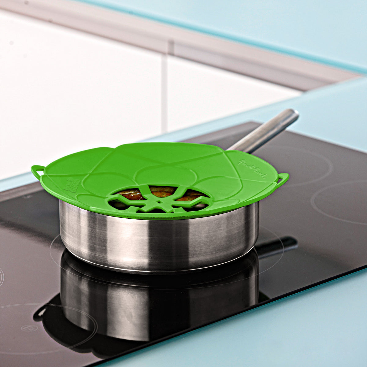 Green lid fits over stainless steel saucepan on stovetop.