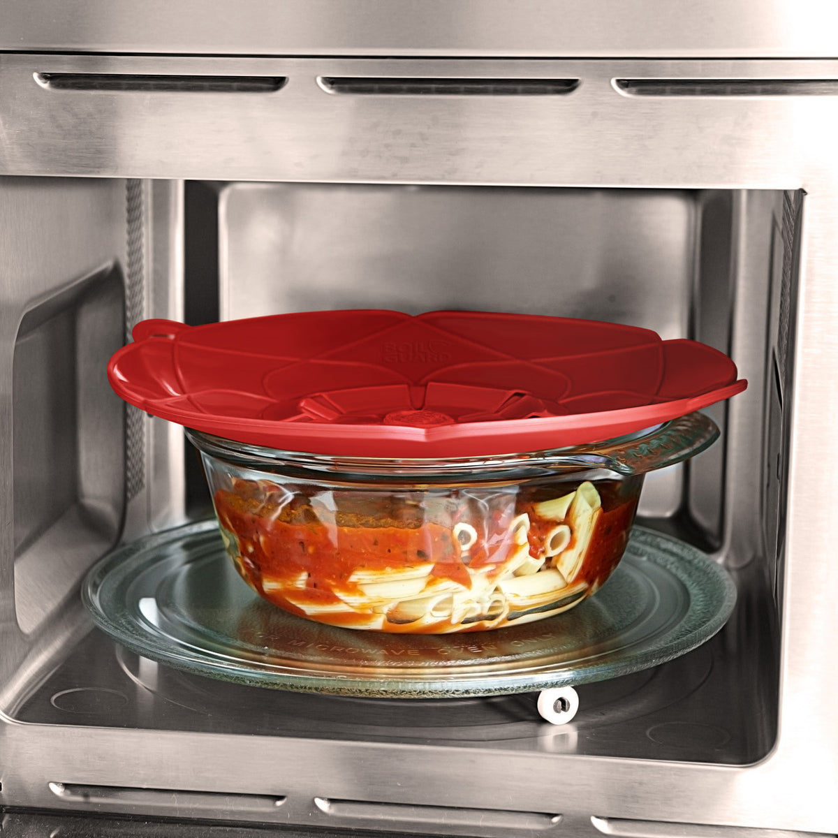 Red lid covers a glass bowl of food inside a microwave.