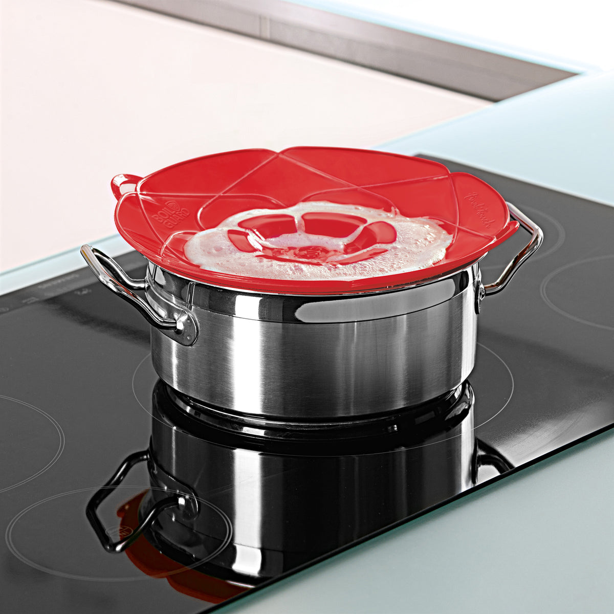 Red silicone lid fits over stainless steel saucepan on stovetop.