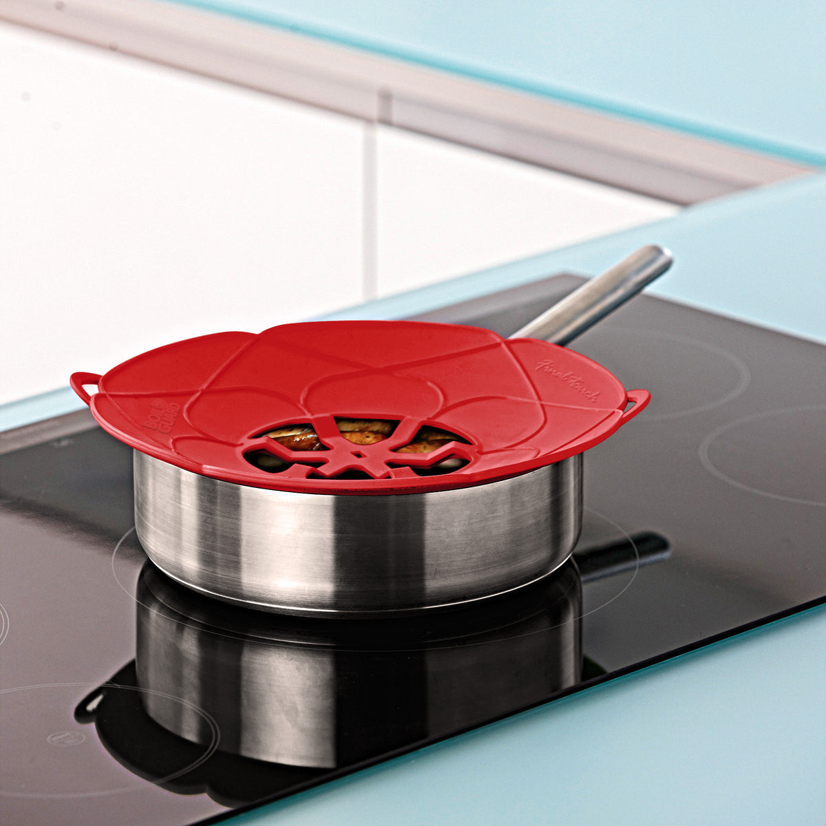 Red Boil Guard lid rests on stainless steel saucepan on modern stovetop.